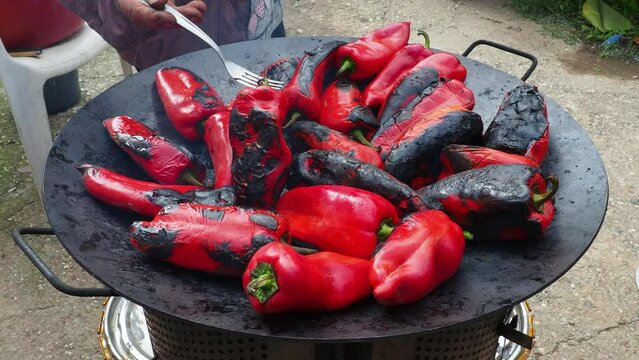Roasting red peppers for a smoky flavor and quick peeling. Thermal processing of the pepper crop on a metal circle. Brazier container used to burn charcoal fuel for cooking, heating or cultural