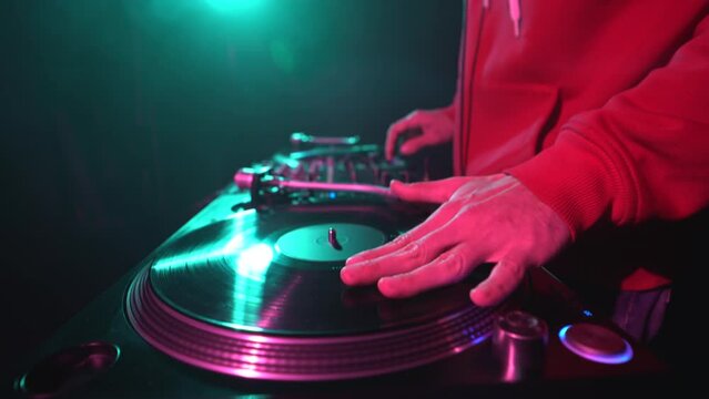 Hip hop DJ scratches vinyl record on turntable. Club disc jocket playing music on party