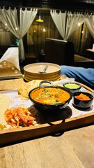 An indian meal with paneer butter masala and naan with papad and other salad