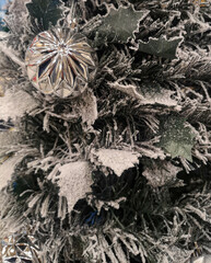 Árbol de navidad con nieve artificial con decoración como las bolas plateadas esperando en una casa a la llegada de papa Noel en una noche muy especial. 