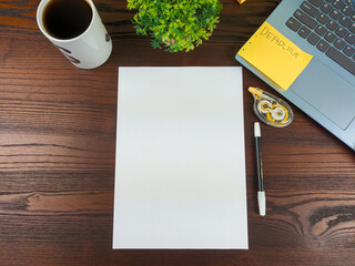 Flat lay, a mockup of a notebook. A workspace with white notebooks, laptops, office supplies, pencils, and coffee cups in the office background of a wooden desk from top view.