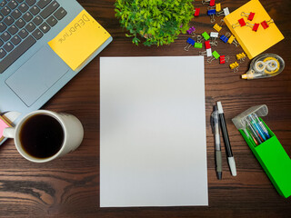Flat lay, a mockup of a notebook. A workspace with white notebooks, laptops, office supplies, pencils, and coffee cups in the office background of a wooden desk from top view.