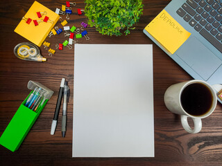 Flat lay, a mockup of a notebook. A workspace with white notebooks, laptops, office supplies, pencils, and coffee cups in the office background of a wooden desk from top view.