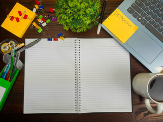Flat lay, a mockup of a notebook. A workspace with white notebooks, laptops, office supplies,and coffee cups in the office background of a wooden desk from top view.