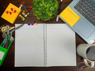Flat lay, a mockup of a notebook. A workspace with white notebooks, laptops, office supplies,and coffee cups in the office background of a wooden desk from top view.