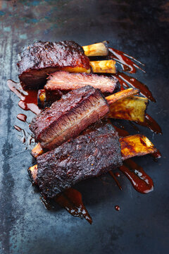 Traditional barbecue burnt chuck short beef ribs marinated with spicy rub and served with a hot chili sauce as close-up on a rustic board 