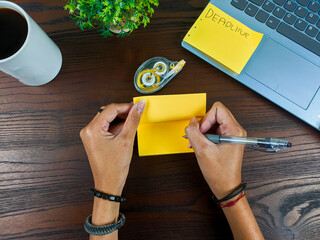 women write in yellow notes, mock up yellow notes. Women's hands write notes on yellow note paper in the background of the office desk workspace from the top view.