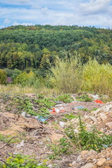 Garbage dump in the mountains. Half-buried garbage in the wooded mountains. Carpathians. Ukraine