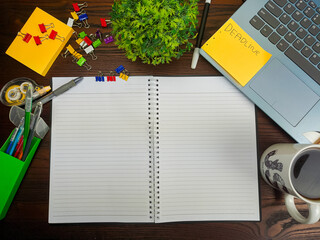 Flat lay, a mockup of a notebook. A workspace with white notebooks, laptops, office supplies, pencils, and coffee cups in the office background of a wooden desk from top view.