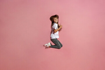 Side view of smiling european little girl jumping