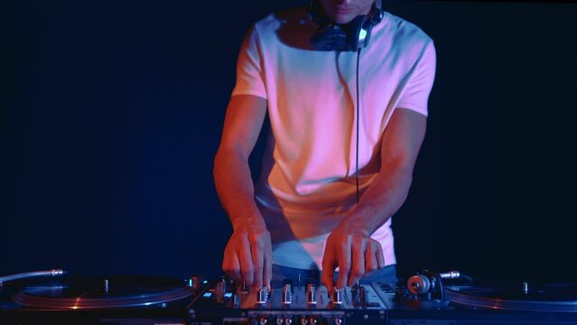 Club dj plays music on party. Hip hop disc jockey mixing vinyl records with sound mixer in night club