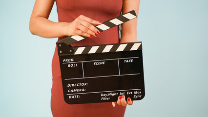 Hand is holding clapper board or clapperboard or movie slate, used in film production and cinema ,movies industry isolated over blue background. - obrazy, fototapety, plakaty