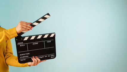 Naklejka premium Hand is holding clapper board or clapperboard or movie slate, used in film production and cinema ,movies industry isolated over blue background.