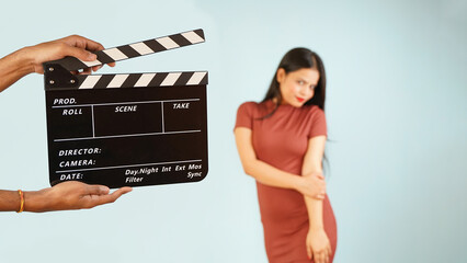 Operator holding clapperboard during the shooting, indoor isolated over blue background