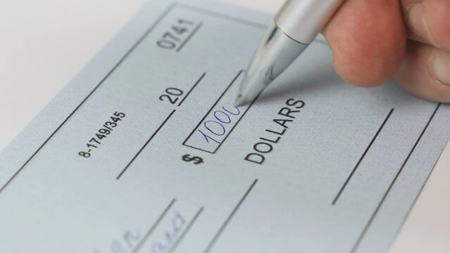 A man writes a bank check for 10,000 dollars. Close-up. Business concept.