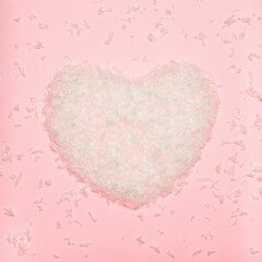 Artificial snow in the form of a heart on a pink background. Christmas concept.