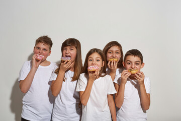 Five caucasian children eat sweet tasty doughnuts