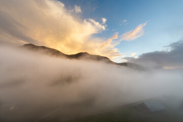 Nebelschwaden ziehen unter einem aufklarenden Himmel nach einem Sommergewitter über die Ackernalm, Tirol, Österreich