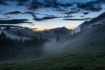 Nebelschwaden ziehen nach einem Sommergewitter in der Abenddämmerung durch die Bergwälder an der Ackernalm, Tirol, Österreich - obrazy, fototapety, plakaty