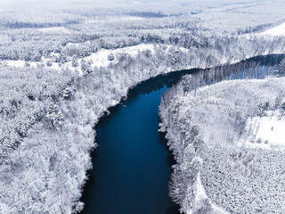 Flying above Brda River and snowy forest in winter, Poland. - obrazy, fototapety, plakaty
