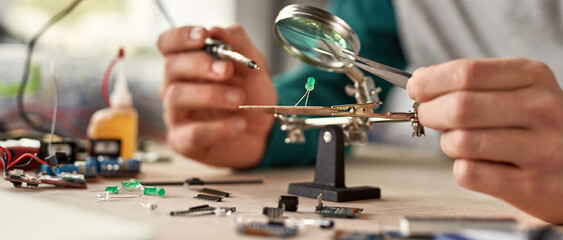 Cropped technician solder chip with soldering iron