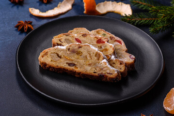 Delicious festive New Year's pie with candied fruits, marzipan and nuts on a dark concrete background