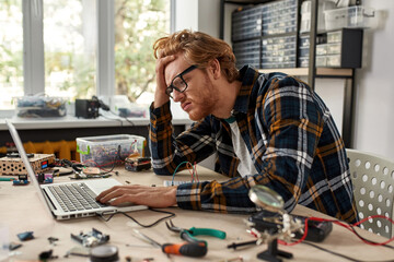 Exhausted male IT technician watch laptop computer