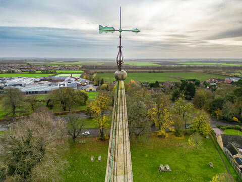 Drone view of a lighting conductor and weather vane seen atop of an English church. Below is part of the church's cemetery.