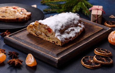 Delicious festive New Year's pie with candied fruits, marzipan and nuts on a dark concrete background