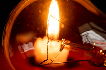 light bulb and candle on black background, blackout	