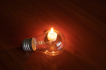 light bulb and candle on black background, blackout	