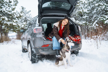 Young woman and cute husky dog enjoying and have fun winter holidays among snowy landace. Travel...