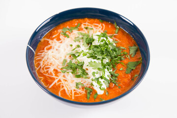 Italian tomato soup served with cream, mozzarella cheese and fresh parsley in a bowl, on a white backgound	

