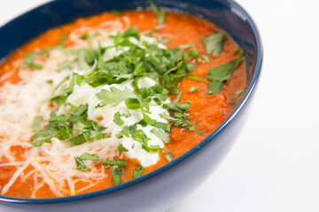 Italian tomato soup served with cream, mozzarella cheese and fresh parsley in a bowl, on a white backgound	
