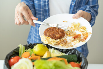 Compost from leftover food, refuse asian young housekeeper woman, girl hand using fork scraping waste from dish, throwing away putting into garbage, trash or bin..Environmentally responsible, ecology.