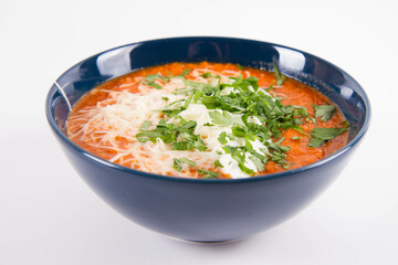 Italian tomato soup served with cream, mozzarella cheese and fresh parsley in a bowl, on a white backgound	
