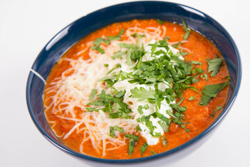 Italian tomato soup served with cream, mozzarella cheese and fresh parsley in a bowl, on a white backgound	
