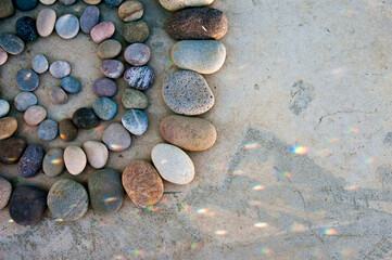 Beach stones in a mandala with scattered light pattern.   - 549259743