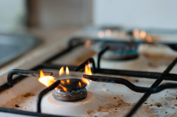 Burning gas in the kitchen. Dirty kitchen stove with a dead fly.