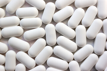 White pills close-up as a medical background. Minimal pharmaceutical concept. Selective soft focus.