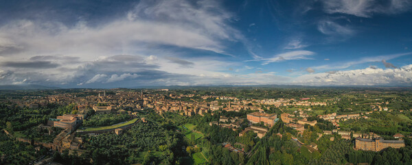 Scenery of Siena, a beautiful medieval town in Tuscany, view of the Dome and Bell Tower of Siena Cathedral, landmark Mangia Tower and Basilica of San Domenico,Italy. Aerial drone shot, october 2022