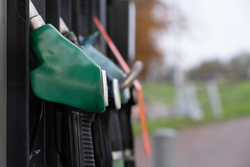 Gas station fuel pumps for different types of gasoline and diesel. Narrow depth of field, focus on the green filling nozzle. Copy space