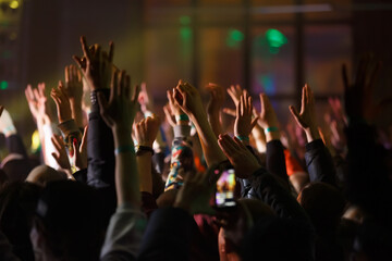 Concert crowd put hands up on dance floor. Group of happy young people enjoying music festival