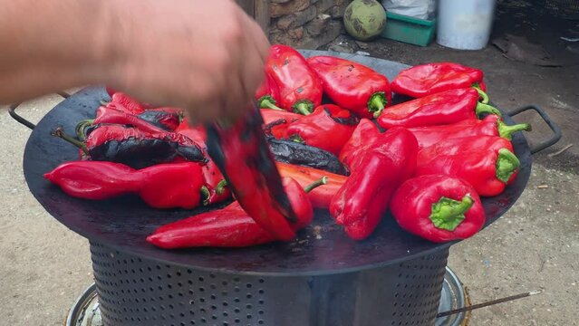 Roasting red peppers for a smoky flavor and quick peeling. Thermal processing of the pepper crop on a metal circle. Brazier container used to burn charcoal fuel for cooking, heating or cultural