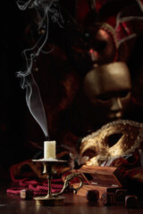 Extinguished candle, dice, and carnival masks on an old wooden table.
