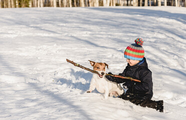 Winter fun outdoor. Boy playing with family pet dog on snow on sunny winter day