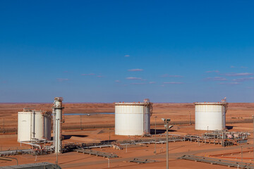 Obraz premium Oil storage tanks, in Algerian desert oil & gas factory under a blue sky 