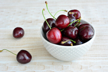 heap of fresh garden cherries in the bowl isolated on pastel background, close-up
