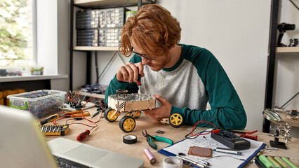 Young IT technician fixing automated wheel robot