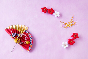 日本の正月イメージ　ゴージャスな赤い扇と紅白のちり緬の梅のデザイン(ピンクの和紙の背景）